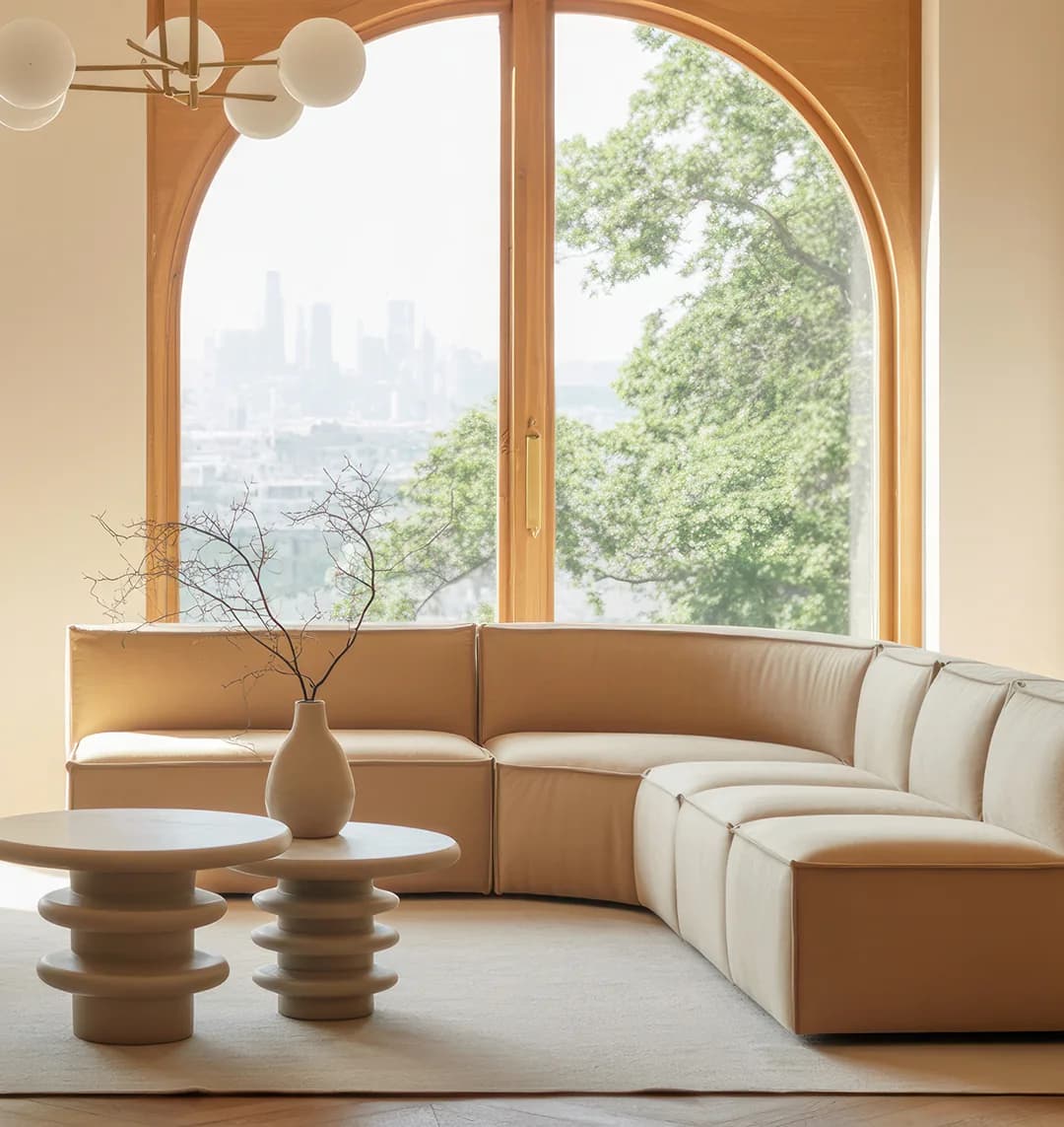 A curved sofa beneath an arched window over the city.