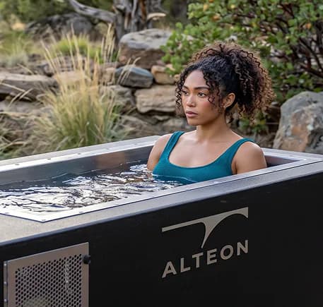 A guest immersed in an Alteon cold plunge tub outdoors.